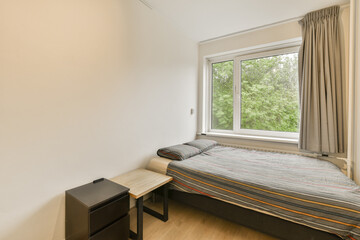 Fototapeta premium a bedroom with a bed, desk and tv in the corner of the room on the left is an open window