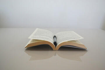 a book and a pen on a table with a white background