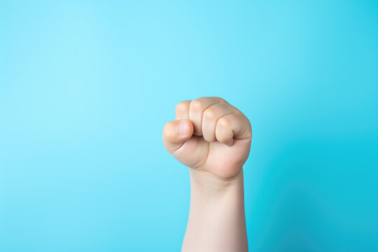 Close-up image of person's fist with vibrant blue background. This powerful and intense photo can be used to portray strength, determination, or symbol of unity.