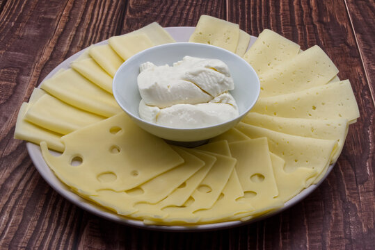 A tray with different types of cheese: emmental, tilsiter, edamer, and a bowl of Italian squacquerone.