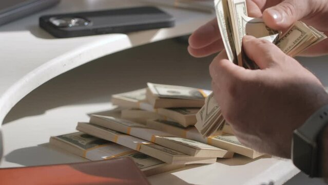 Male hands counting dollar banknotes sitting in room at table. Banking and finance. Business lifestyle. Rich man hands holding cash money in bank cabinet. Financial job concept. Close up shot
