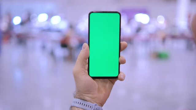 POV, male hand using smartphone with green screen chroma key in the shopping mall