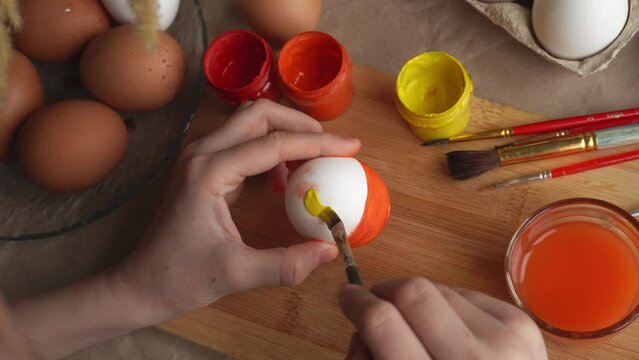 Preparation for Easter. A child paints an Easter egg with bright colors