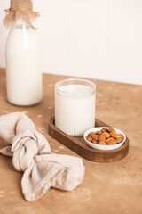 Organic almond milk in glass near the bowl with raw almonds on the table in the kitchen ready for cooking