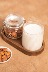 Organic almond milk in glass near the bowl with raw almonds on the table in the kitchen ready for cooking