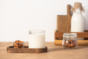 Organic almond milk in glass near the bowl with raw almonds on the table in the kitchen ready for cooking