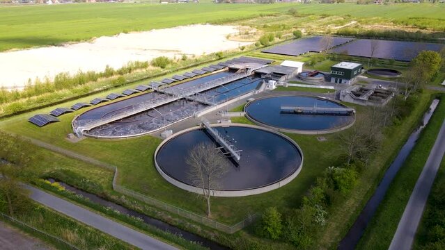 Panoramic aerial shot of a large water treatment plant with agitation tanks and aeration chamber located on a grassy countryside landscape