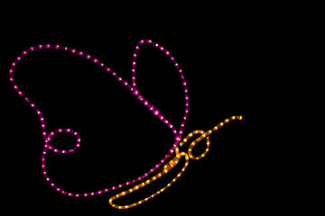 Illuminated LED lamp in the shape of a neon butterfly on a black background, glowing garden ornaments, Christmas decorations

