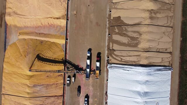 Drone view over two grain storage piles being filled and covered