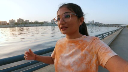 Selfie video of Indian teenager girl vlogging at Sabarmati river front in Ahmedabad, Gujarat, India.  Travel influencer exploring city and making video for social media. Young travel influencer.