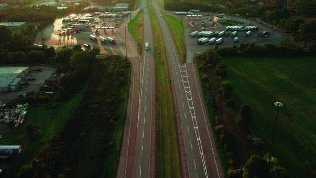Magic aerial of semi truck on interstate between service plaza area. Sunset