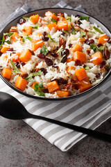 Basmati rice with sweet potato, nuts, pecans, onions and dried cranberries close-up in a bowl on the table. Vertical