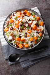 Basmati rice with sweet potato, nuts, pecans, onions and dried cranberries close-up in a bowl on the table. Vertical top view from above