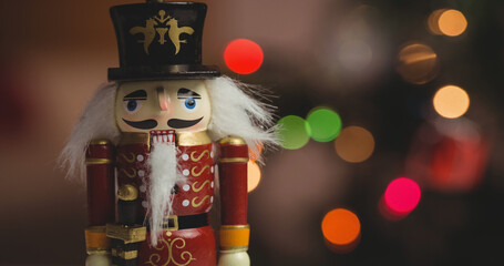 Traditional wooden nutcracker soldier figure over coloured bokeh christmas lights background