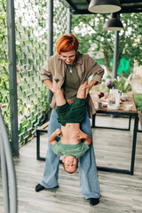 Family mother with her son holding on her hands playful mommy love enjoy time at the terrace redhead woman with short haircut