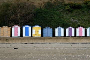 Obraz na płótnie Canvas Idyllic beach scene featuring multicolored beach huts lined up in a row.