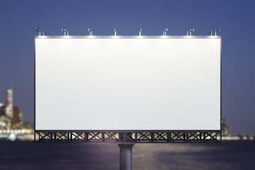 Blank white billboard on city buildings background at night, front view. Mockup, advertising concept