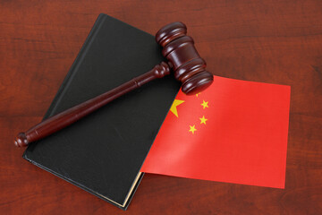 Wooden judge gavel and legal book with flag of China on wooden table