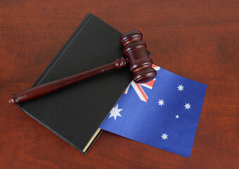 Judge gavel and legal book on wooden table with flag of Australia