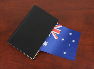 Black book and flag of Australia on table.