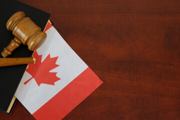 Broken gavel and legal book with flag of Canada on wooden table. Copy space for text.