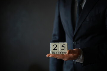 Portrait of  businessman ready for Christmas. Wooden cubes with inscription 25 december
