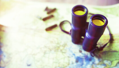 Binoculars and map on wooden table. Top view traveler essentials concept.