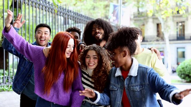 Happy playful multiethnic group of young friends standing together outdoors - multiracial millennial students meeting in the city, concepts of youth, diversity, teenagers and urban life