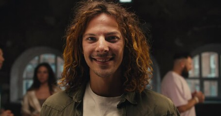 Portrait of a Happy man with curly hair in a Green jacket looking at the camera amid other participants during group therapy. Group therapy client and participant