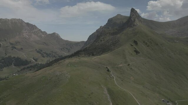 Drone footage over the grassy mountains around the Bannalpsee reservoir on a sunny day, Switzerland