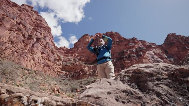 Young male tourist takes a photo on his phone's camera during a hike in the Grand Canyon Arizona desert