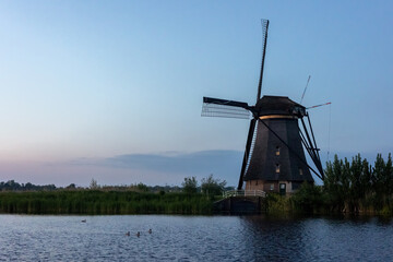 Beautiful wooden windmills at sunset in the Dutch village of Kinderdijk. Windmills run on the wind. The beautiful Dutch canals are filled with water. Beautiful sunset. - 670419583