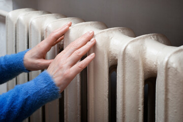 Caucasian female hands touching Hot Water Radiator. Home heating concept. Space for text
