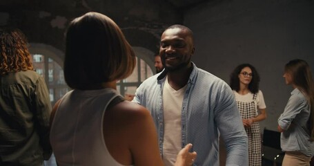 A black man in a Blue shirt and a girl with a bob hairstyle hug at group therapy in a brick building. Achieving mutual understanding and pleasant communication in group therapy as a consequence of