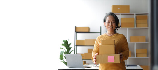 Senior female entrepreneur, small business owner, online seller working with parcel boxes preparing...