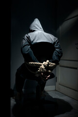 The man was sitting on a chair with tied hands in ropes