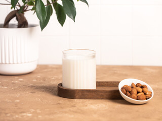 Organic almond milk in glass near the bowl with raw almonds on the table in the kitchen ready for cooking
