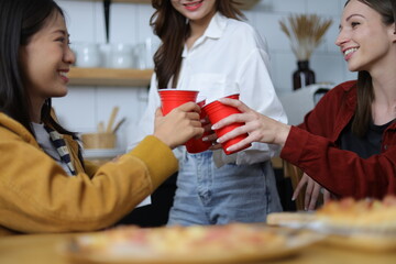 Young woman and friends having a small party in the kitchen at home.