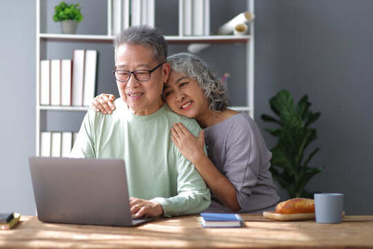 Happy senior couple in retirement at home. Men and women are using laptop in the home office.