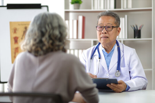 Senior health care concept. Doctor with patient in medical office. Retired woman sits in a hospital examination room while discussing his health with a doctor.