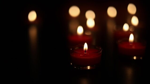 Burning candles on dark surface. Many burning candles with shallow depth of field.