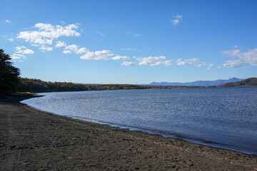 青空と湖畔の湾曲した砂浜