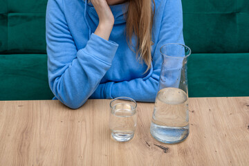 Kobieta siedzi w restauracji, na stoliku jedynie dzbanek z wodą i szklanka wody - obrazy, fototapety, plakaty