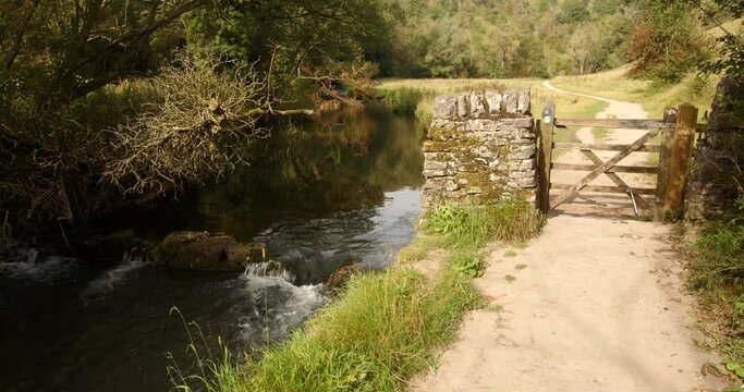 Wide Shot of a gate midway through the dovedale walk with the river dove on the left hand side