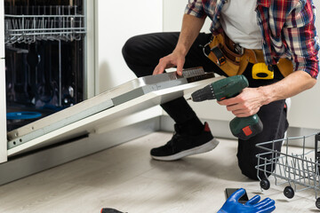 Male Technician Examining Dishwasher With Digital Multimeter
