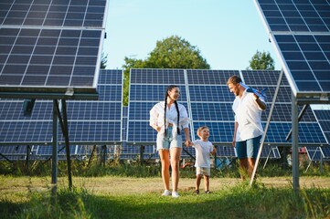 Enthusiastic father showing potential of alternative energy. Contemporary family looking at new solar station they bought. Side view of happy parents and interested child next to solar panels