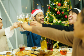 Group of diverse ethnicity young people enjoy celebrating a Christmas and New Year party together with a lot of foods and drinks. Friends celebrate Christmas and New Year festival and drink a wine.