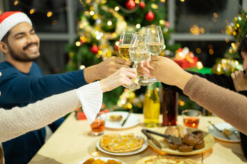 Group of diverse ethnicity young people enjoy celebrating a Christmas and New Year party together with a lot of foods and drinks. Friends celebrate Christmas and New Year festival and drink a wine.