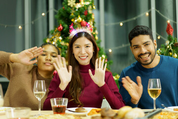 Group of diverse ethnicity young people enjoy celebrating a Christmas and New Year party together with a lot of foods and drinks. Friends celebrate Christmas and New Year festival and drink a wine.