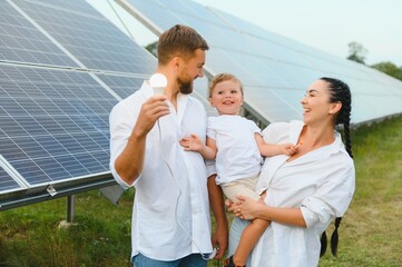 The concept of renewable energy. Young happy family near solar panels